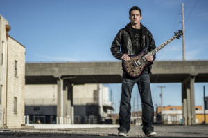Photo of guitarist Chase Whiteside standing in an empty ally.