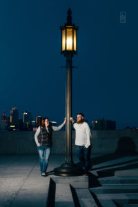 Dave and Bethany Strieff both pose near a lamp on top the world war one memorial in kansas city